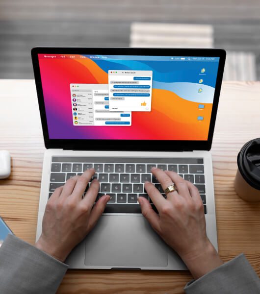 Person's hands typing on a laptop keyboard with a colorful screen display showing messaging applications.